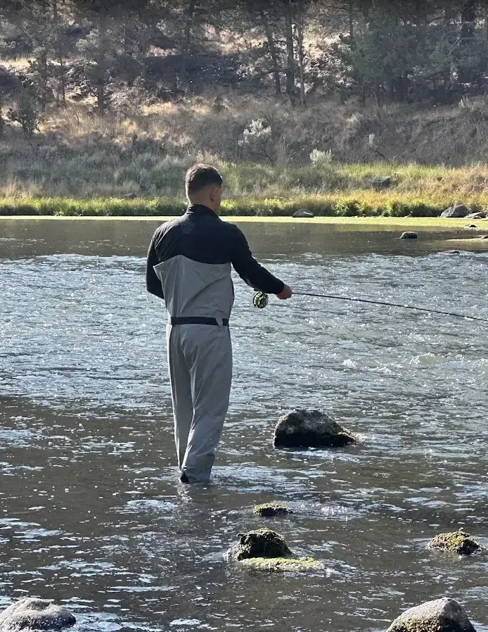 An angler wading a Central Oregon river while fly fishing