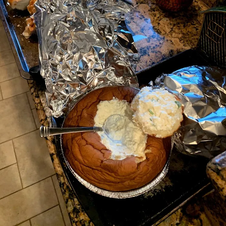 Clam dip served in a hollowed-out bread bowl with torn bread for dipping