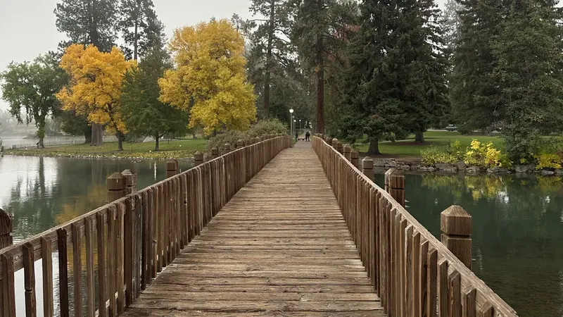 A wooden footbridge and yellow fall trees over the Deschutes River in Bend, Oregon