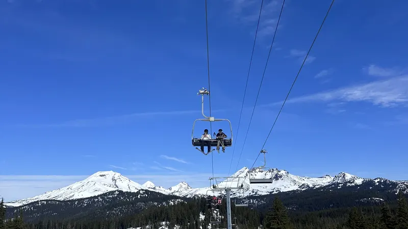 A chairlift over snowy slopes at Mt. Bachelor with the Three Sisters behind it