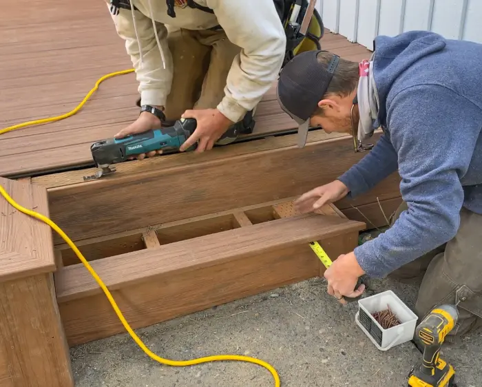 Two carpenters fitting a stair box into a new composite deck frame