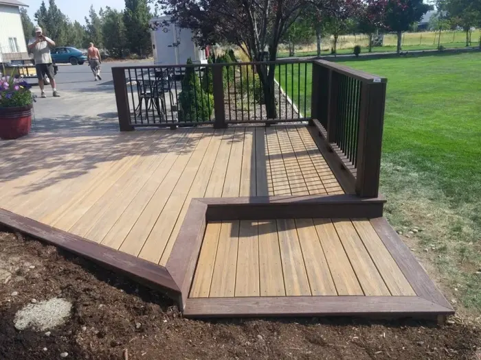 A new low wood deck with a picture-framed border and black metal railing in a Bend backyard